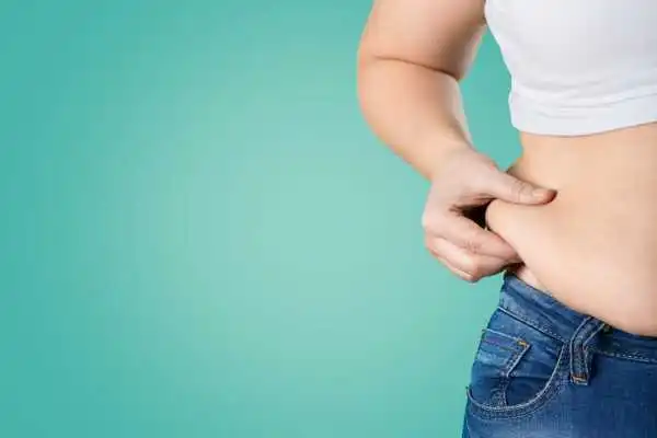 Image of woman pinching her love handles to show weight gain Shepperton Green